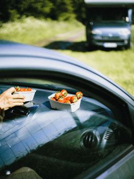 A close-up of strawberries on a car dashboard with a hand nearby, capturing a summer outdoor vibe.
