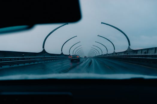 Interior view from a car driving on a rainy highway tunnel with futuristic design, capturing a moody atmosphere.