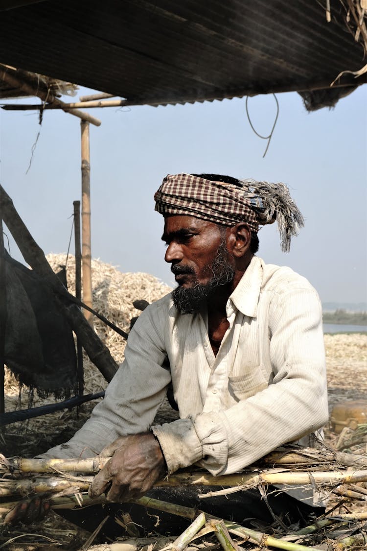 Old Man In Headwear Working On Cropland