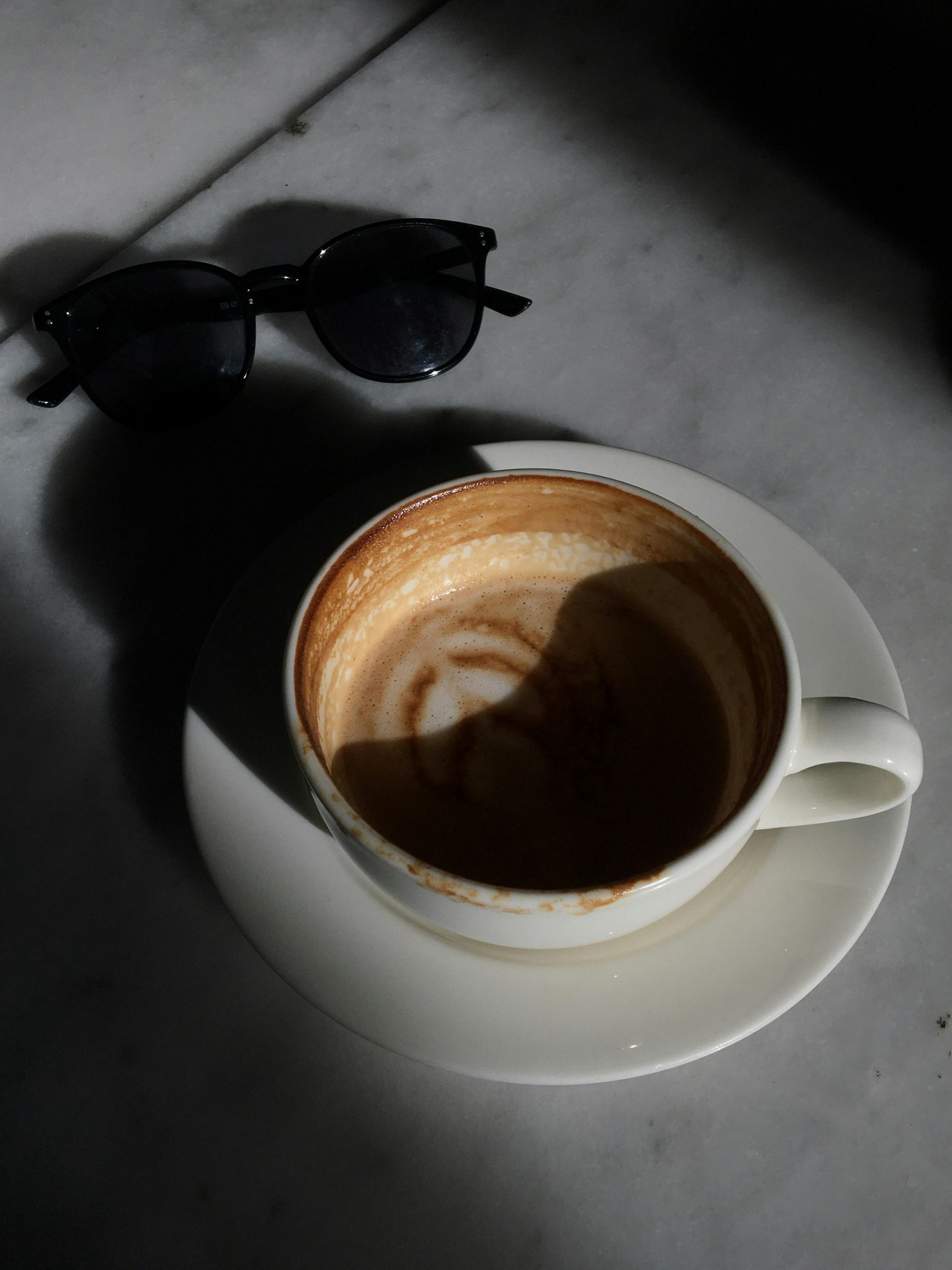 Gorgeous brunette woman in sunglasses drinking coffee and taking picture of  herself in weekend. Amazing tanned female model making selfie while  enjoying latte in outdoor restaurant. Stock Photo | Adobe Stock