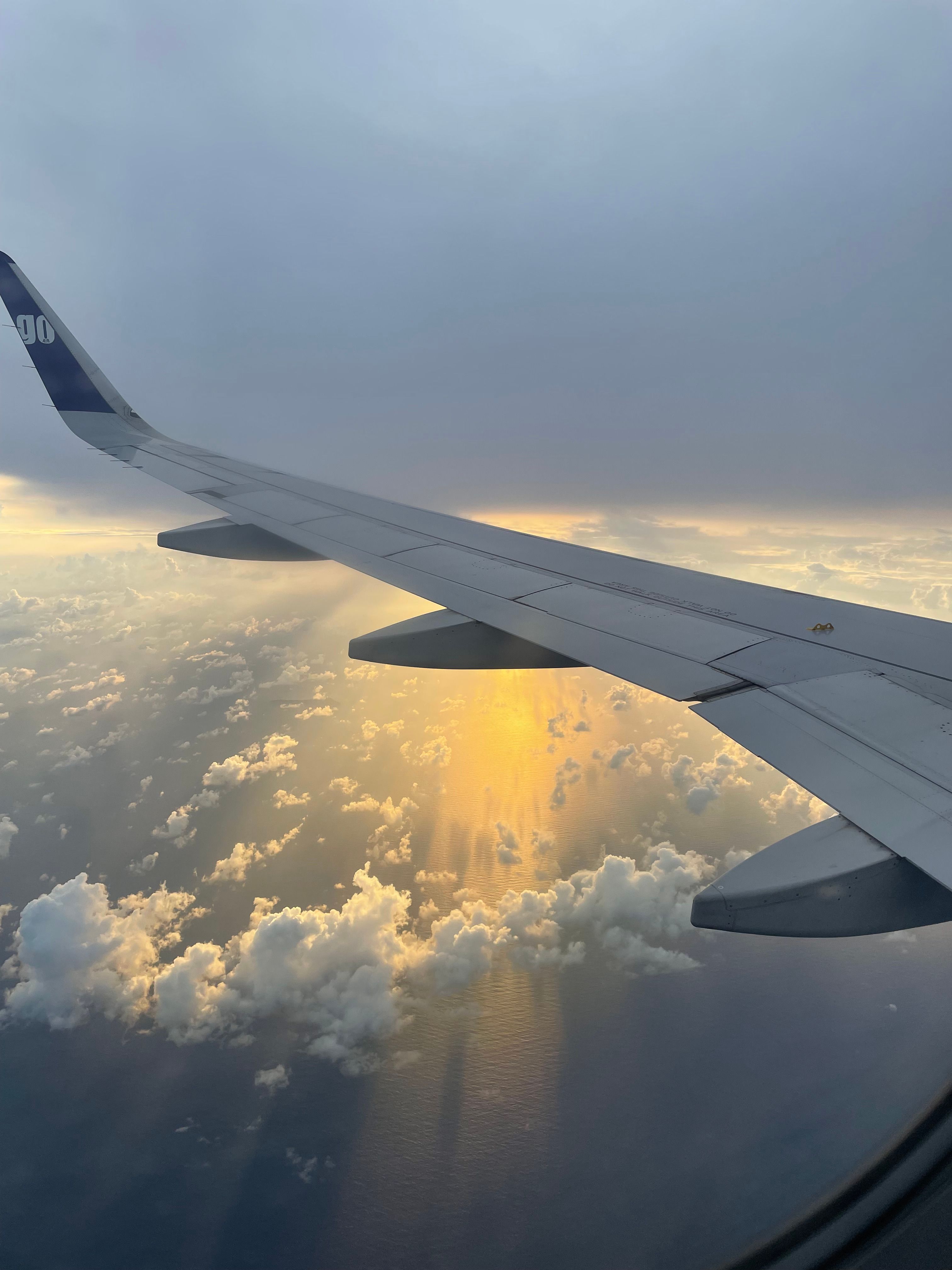 An airplane wing above the clouds at sunset