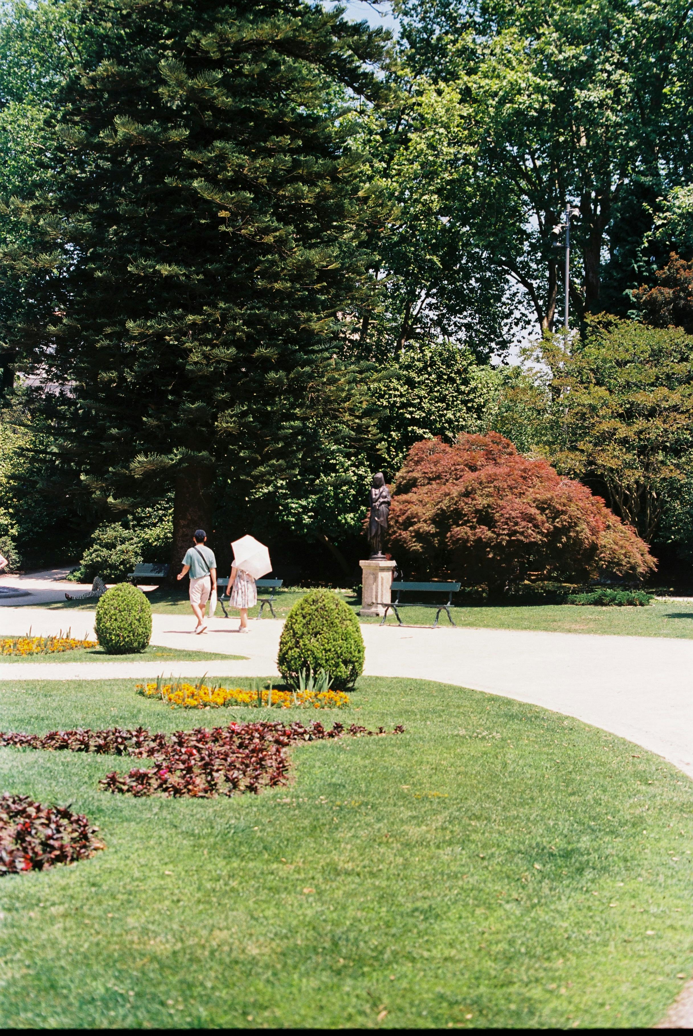 A peaceful summer scene in a lush park in Porto, Portugal with people strolling.