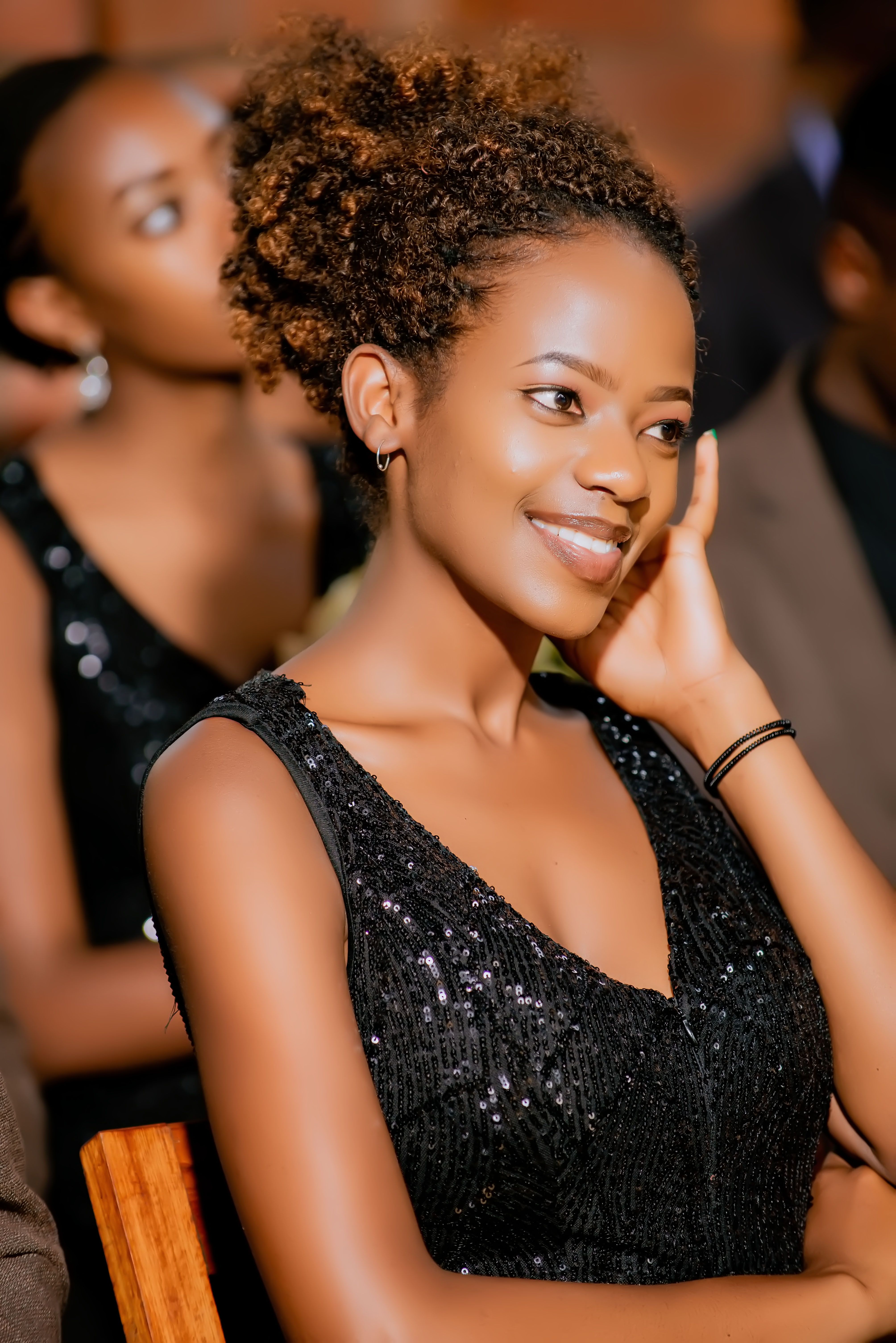 Portrait of a smiling woman with afro hair in an elegant black dress, indoors.