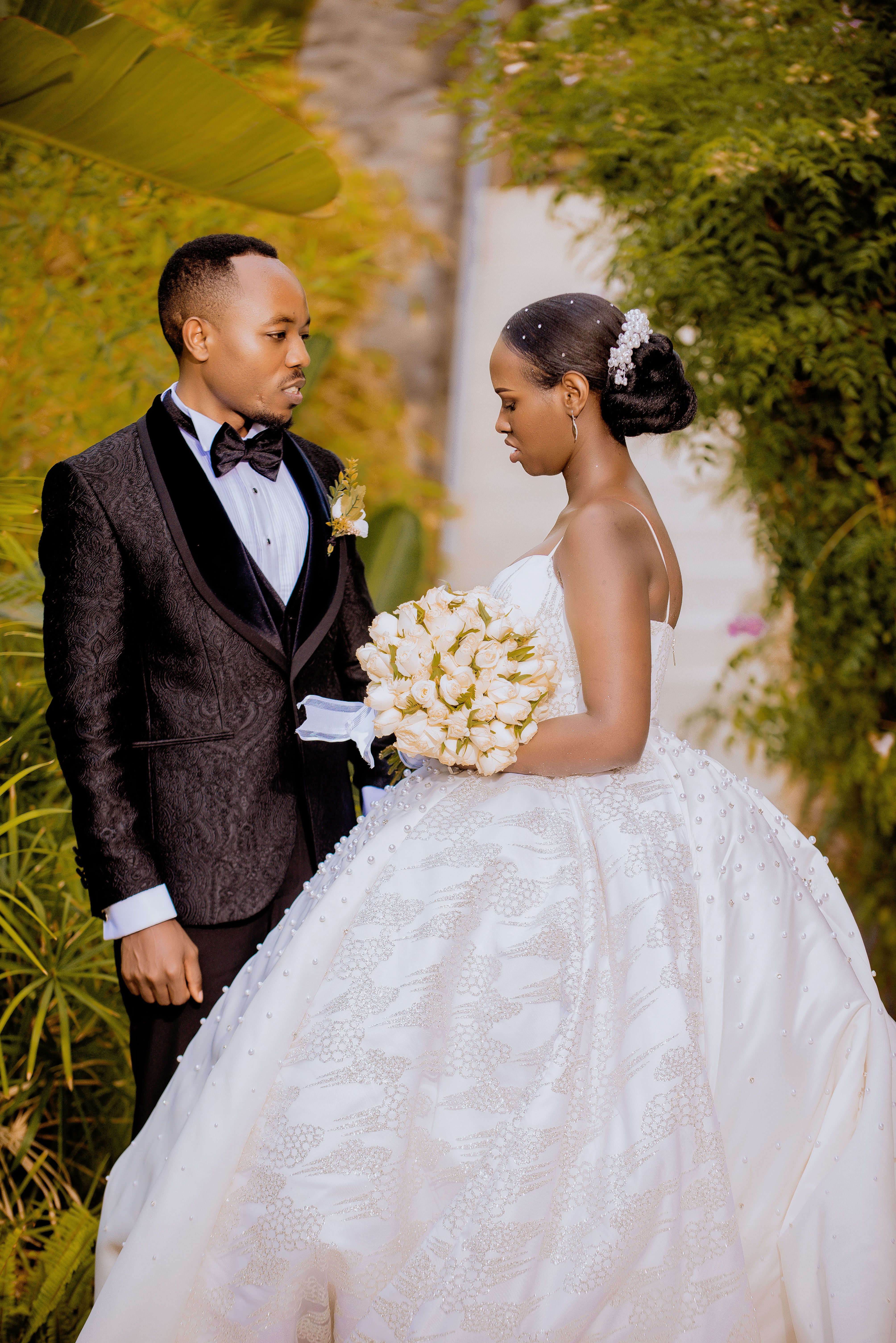 An elegant bride and groom in a wedding attire, captured in a lush garden setting, showcasing love and elegance.