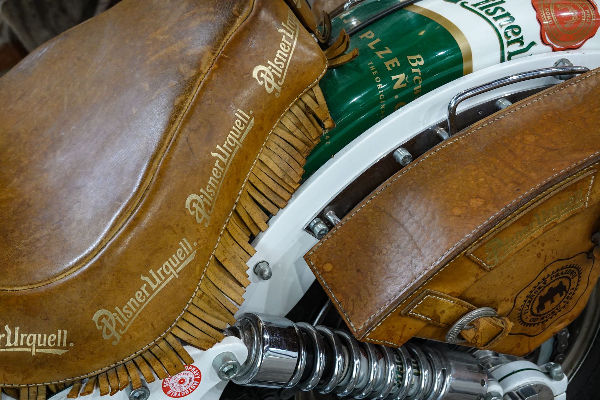 Close-up of a vintage motorcycle featuring bespoke leather saddle with brewery branding.