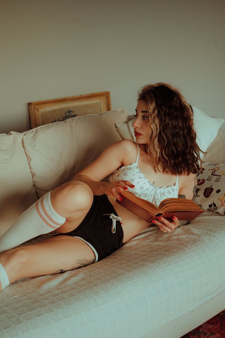 Woman Lying Down On Bed With Book