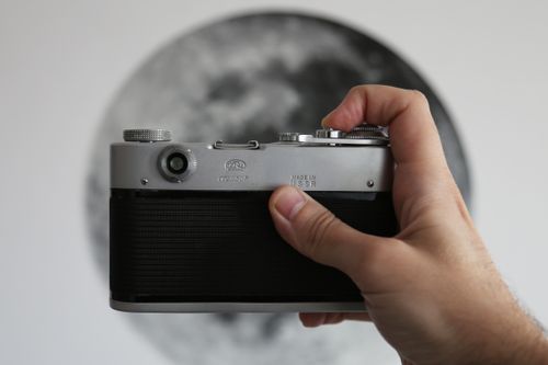 Free Close-up of a vintage camera held by a hand with an artistic background. Stock Photo