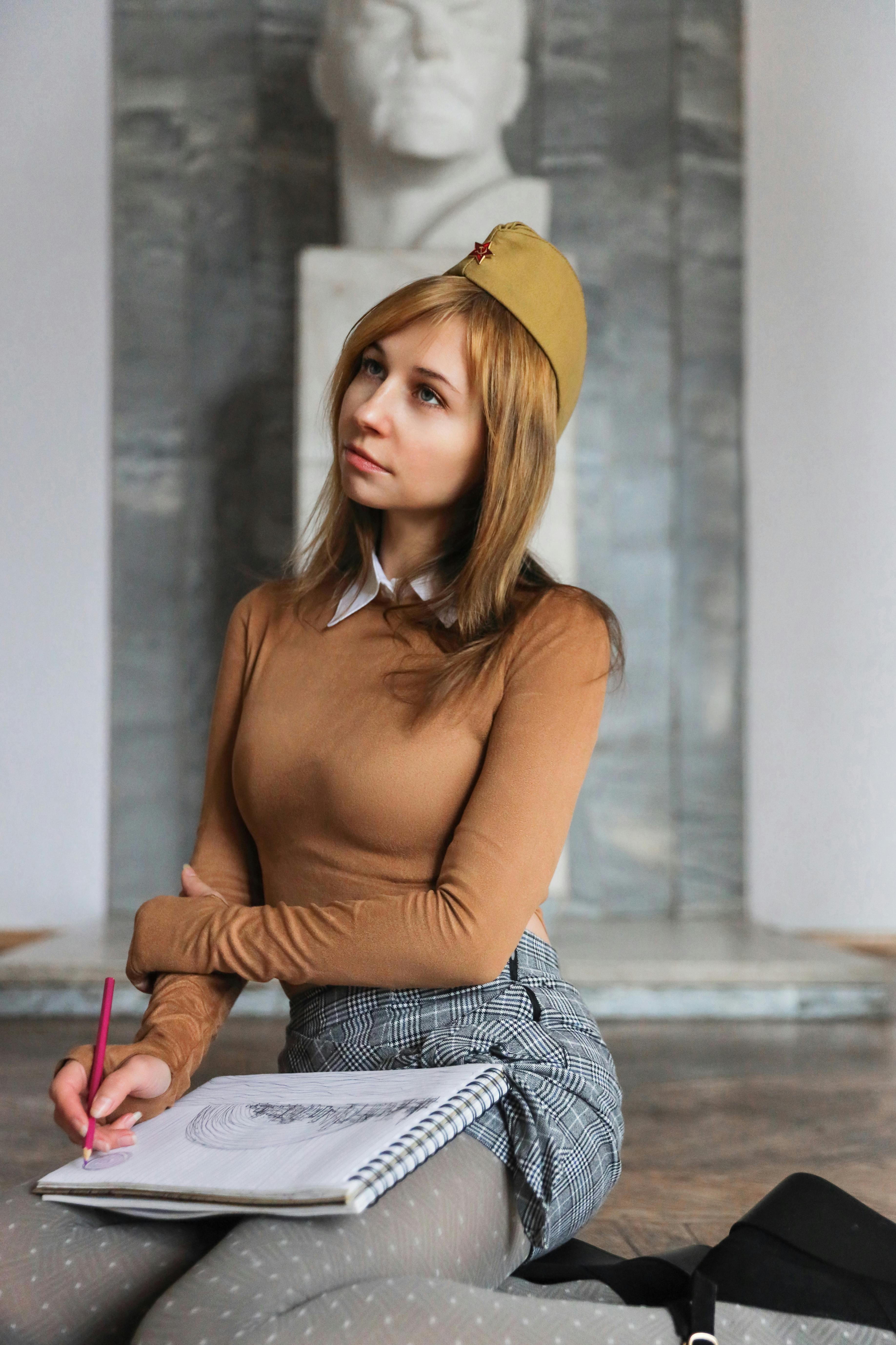 A young woman in a museum sketching with focused concentration.