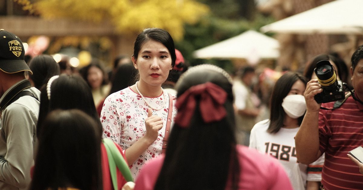 Asian woman with pearl necklace amidst a bustling street crowd in Ho Chi Minh City.