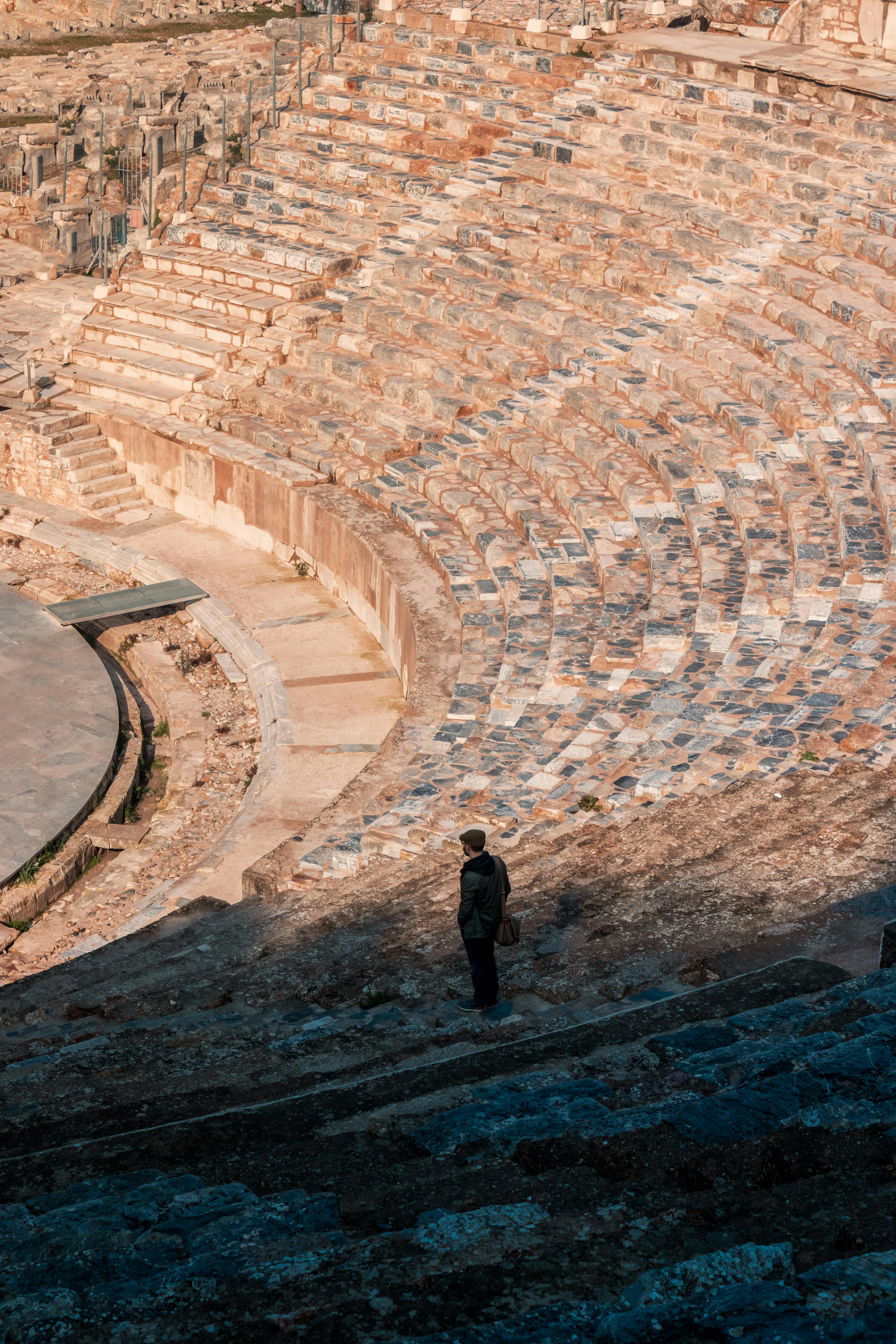 Free Discover the historic amphitheater in İzmir, Türkiye with a lone traveler exploring its ancient steps. Stock Photo