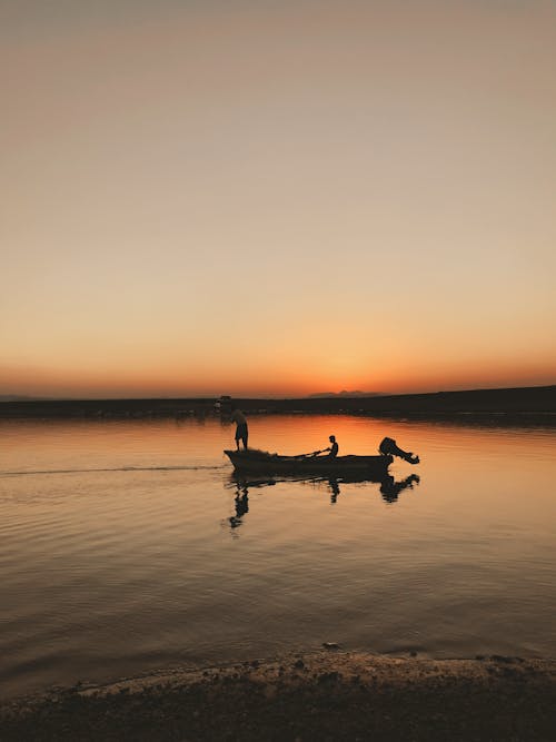 Silhouette of Men on a Boat at Sunset 