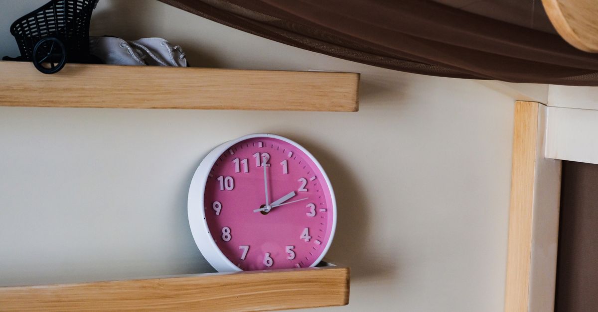 Horloge rose élégante accentuant un décor intérieur moderne avec des étagères en bois.