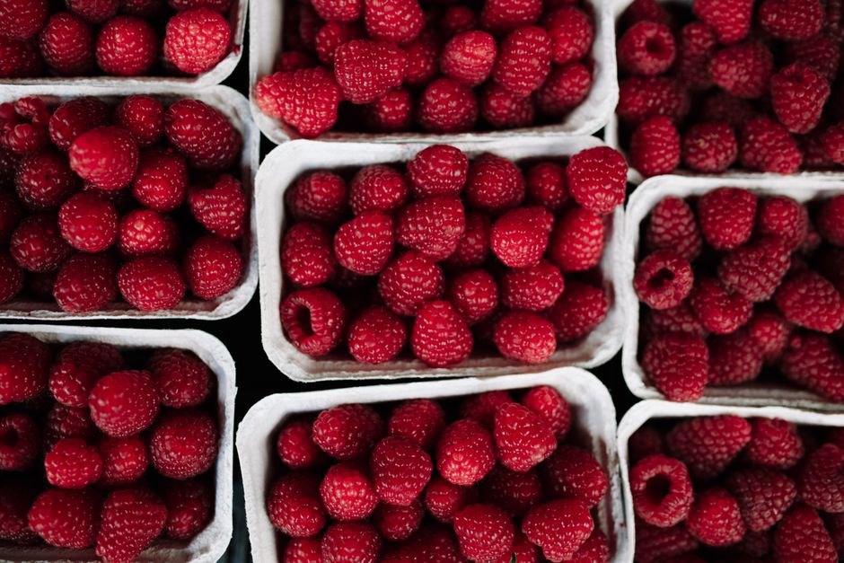 Close-up of fresh, organic raspberries neatly arranged in eco-friendly paper boxes.