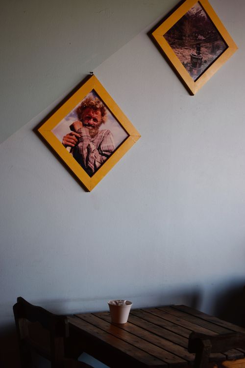 Free A cozy cafe corner with rustic wooden furniture and framed portraits on the wall. Stock Photo