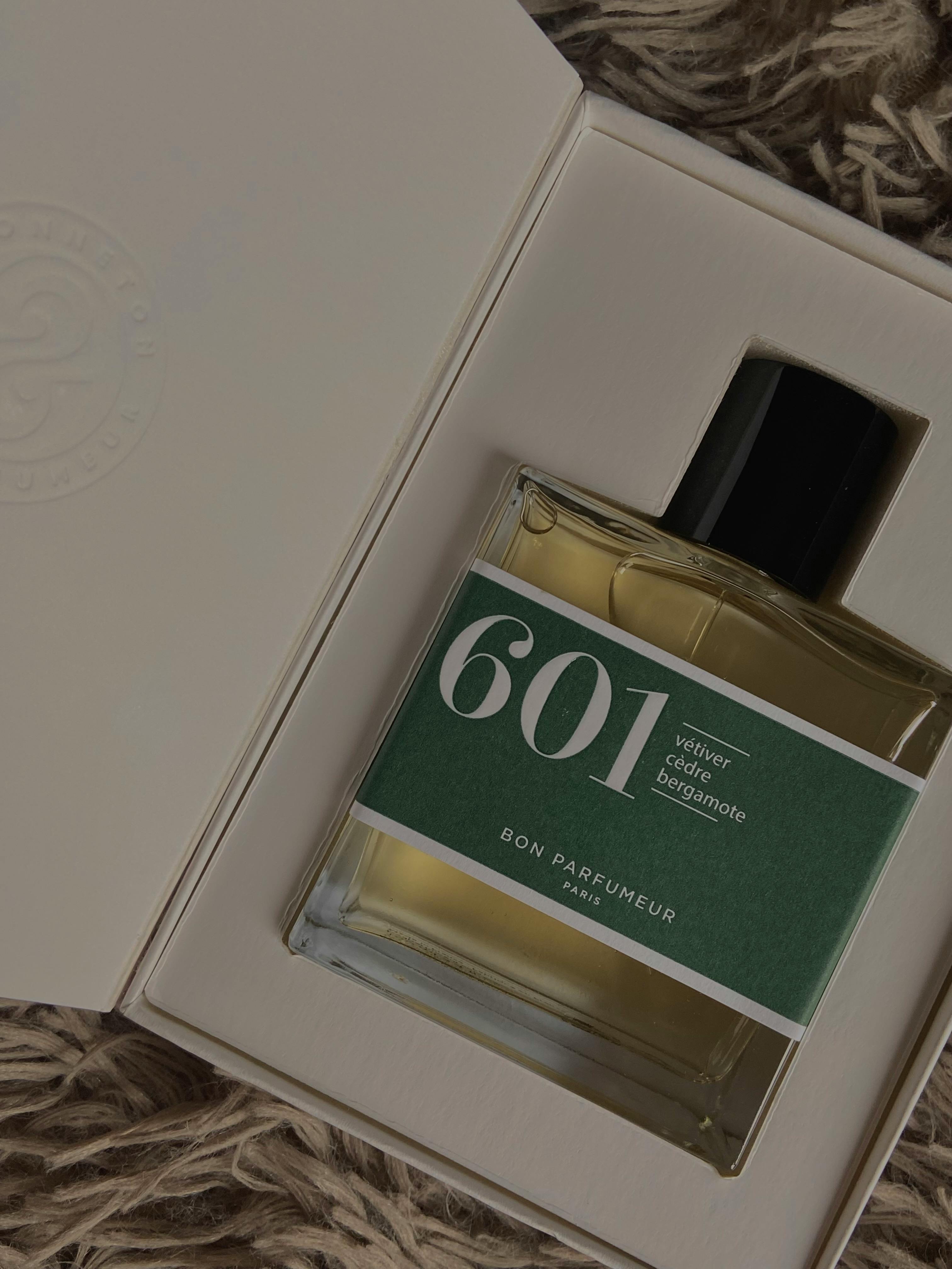 Close-up of a perfume bottle in an open box with textured surroundings.