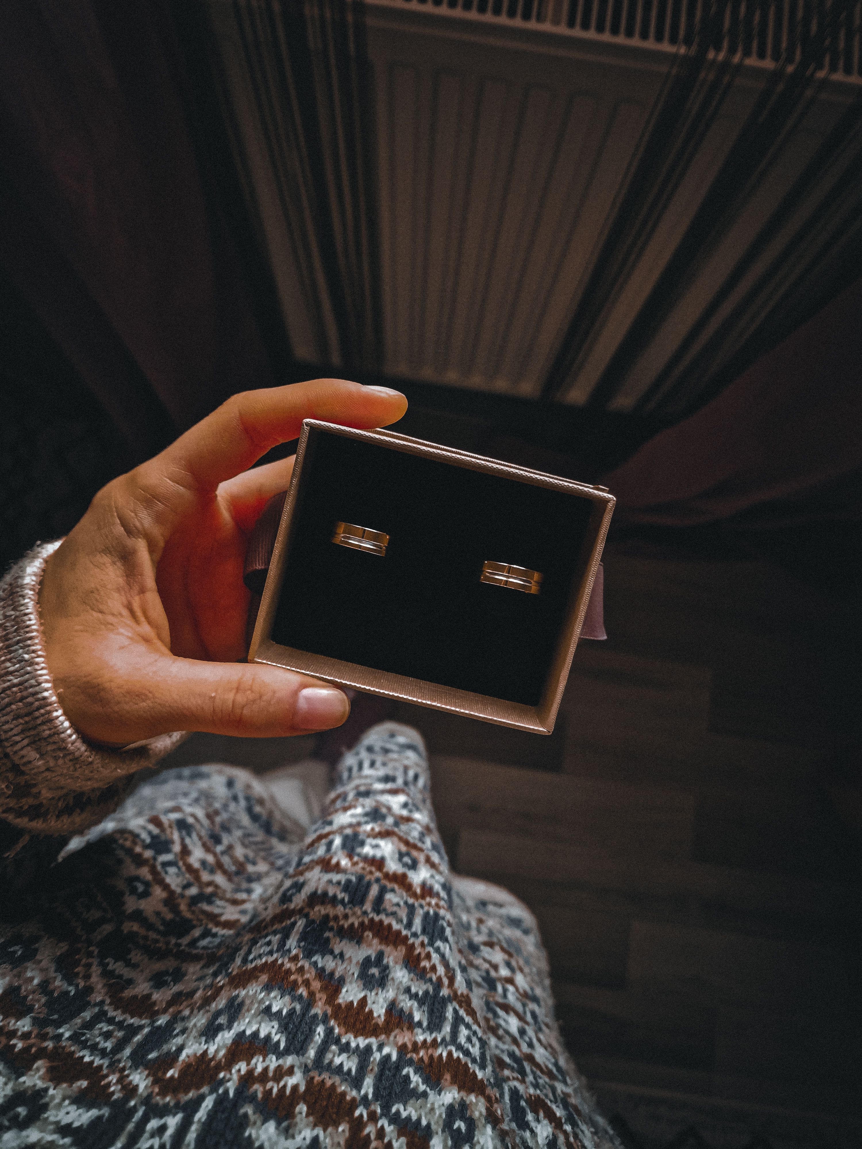 Personne tenant un écrin à bijoux ouvert avec des bagues à l'intérieur
