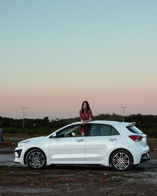 Photograph of a Woman Standing in a White Car