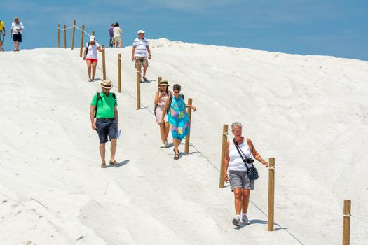 Visitors enjoying a sunny day walking on a vast white sand dune trail.