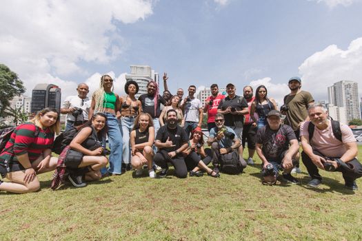 Group of diverse photographers posing outdoors on a sunny day.