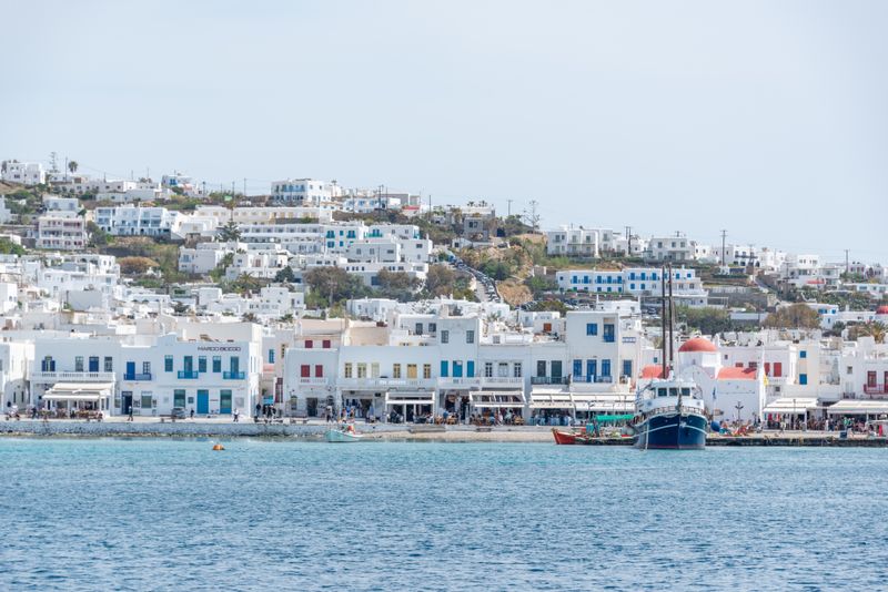 Charming Mykonos harbor with white Cycladic buildings and a colorful ship.