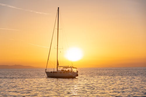 Photo of a Sailboat on the Sea during Sunset