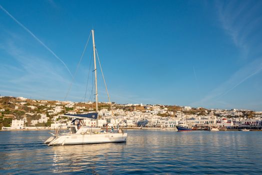 Idyllic view of Mykonos harbor with boats and white architecture under a clear summer sky.