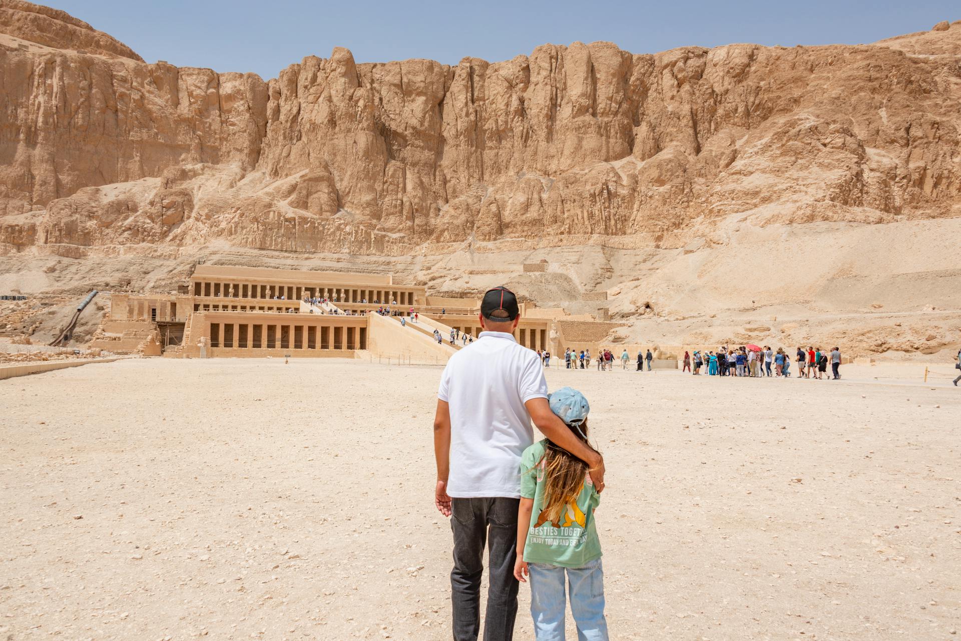 A father and daughter standing before the Mortuary Temple of Hatshepsut in Egypt, a popular tourist destination.