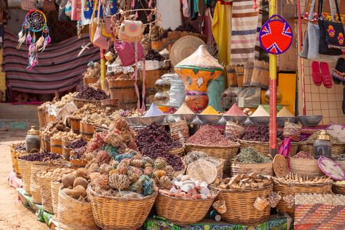 Free Colorful market stall featuring a variety of spices, wicker baskets, and handmade crafts. Stock Photo