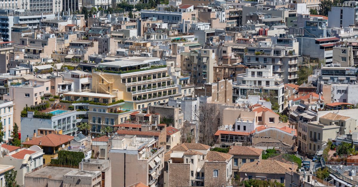 Panoramic aerial view of Athens featuring dense residential buildings under a clear sky.