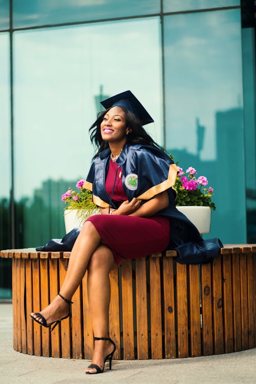 Woman in a Graduation Gown Sitting outside a Building 