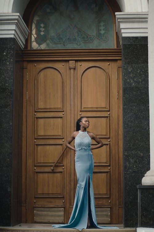 Woman in Long Gown Standing in Front of Wooden Doors