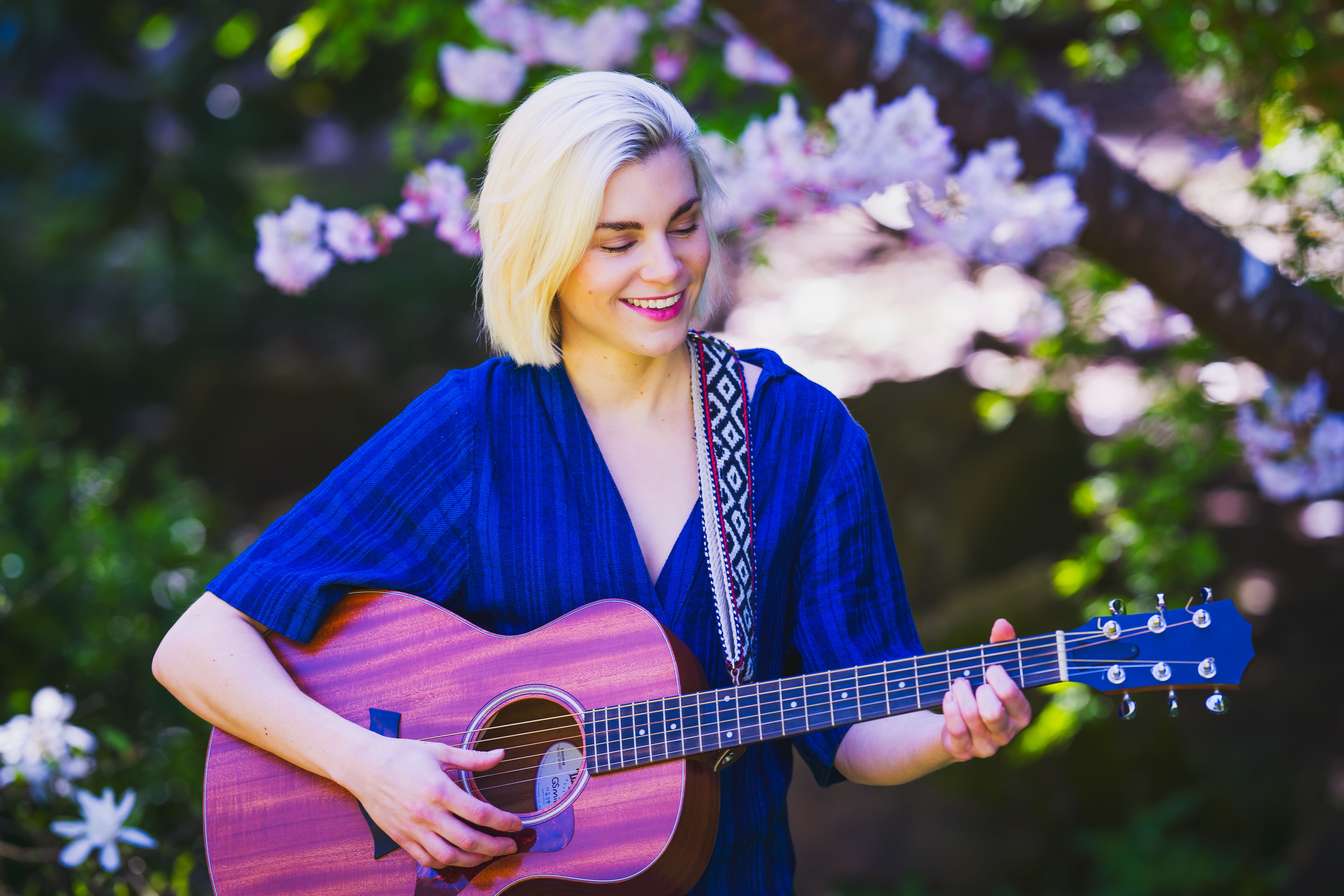 Young Woman Playing Guitar under a Magnolia Tree  Free Stock Photo