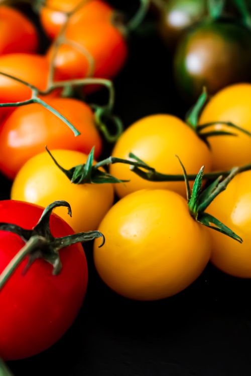 Free Close-up of colorful cherry tomatoes in studio, highlighting vivid colors with a black background. Stock Photo