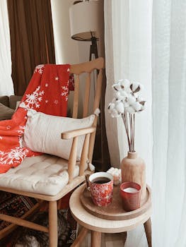 Warm and inviting home decor featuring a cozy armchair, red blanket, and decorative textiles.