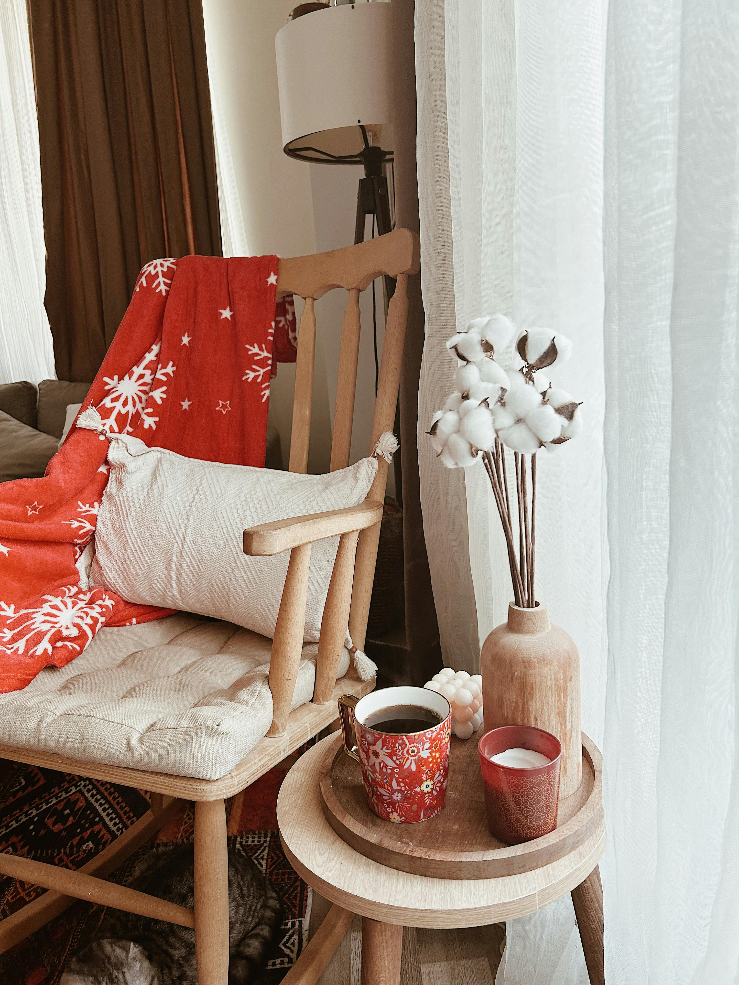 Free Warm and inviting home decor featuring a cozy armchair, red blanket, and decorative textiles. Stock Photo