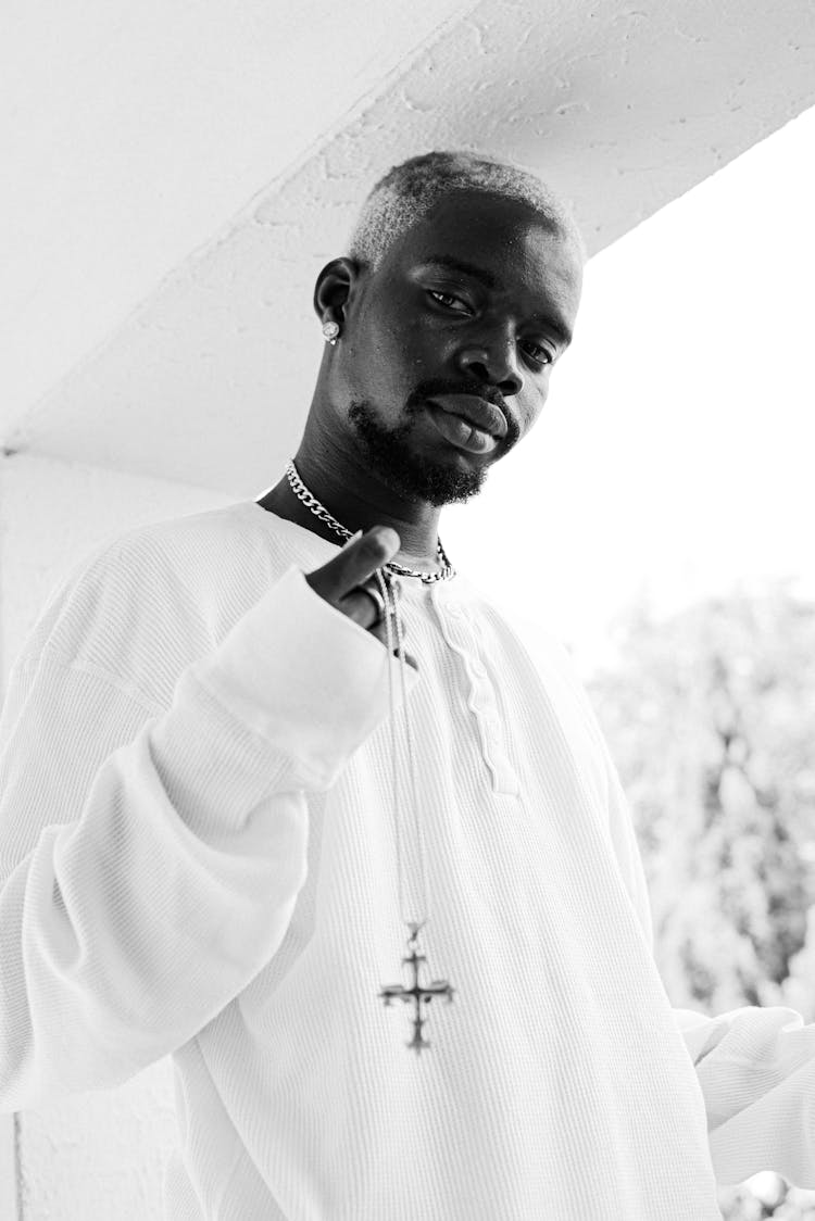 Man In A White Sweatshirt Standing And Holding A Cross On A Chain 