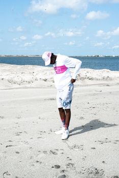 Man in casual outfit enjoying a sunny day on a scenic beach with blue sky.