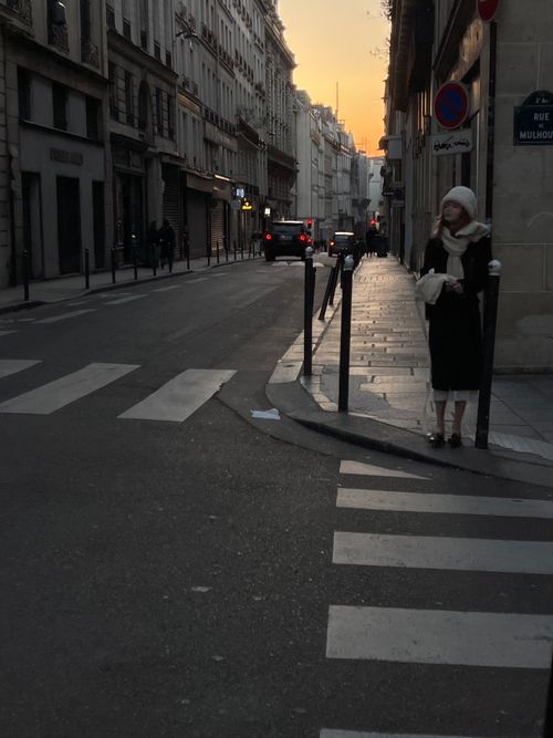 Free A woman in a black dress stands on an urban street at dusk, capturing a trendy city vibe. Stock Photo