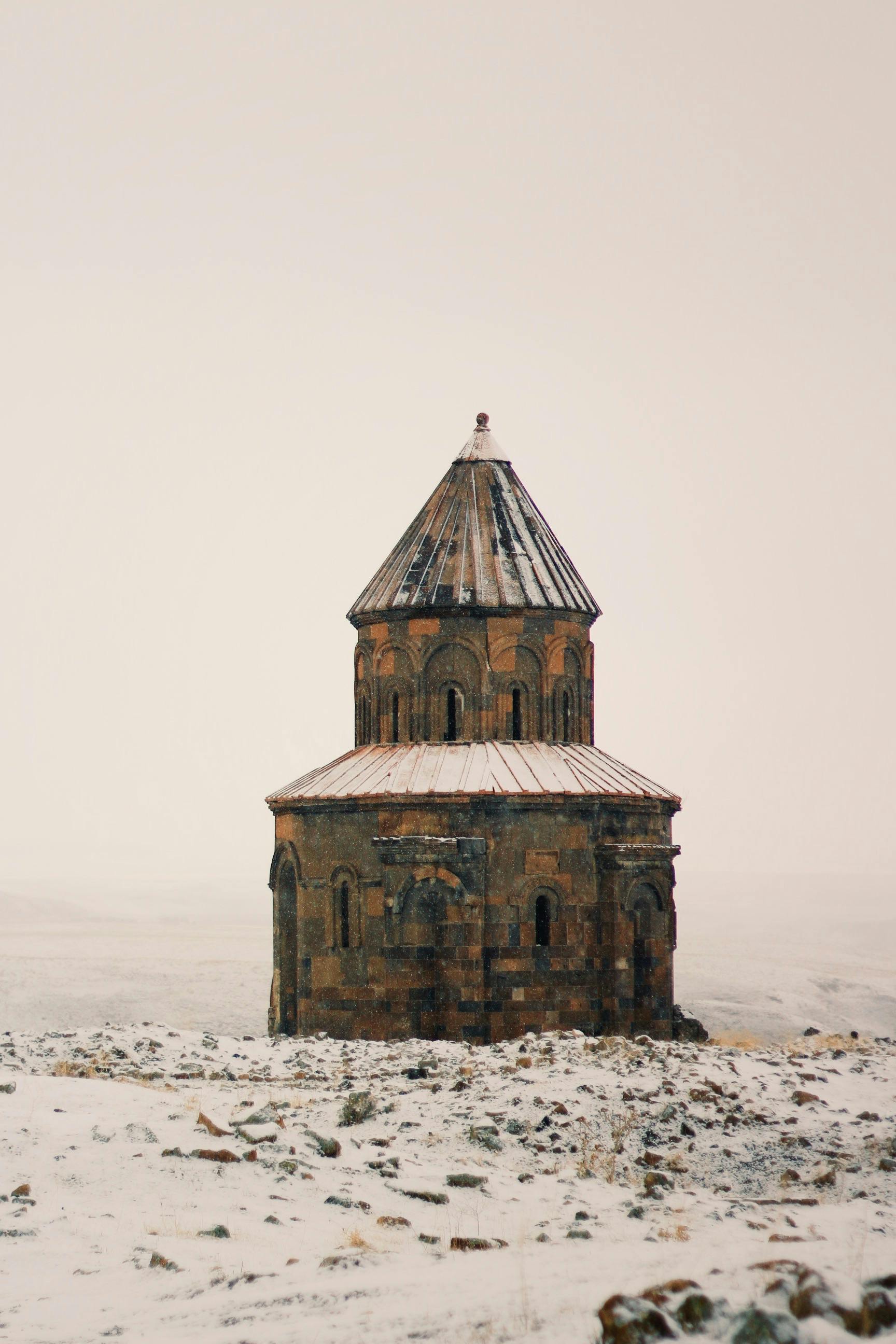 A solitary gothic chapel stands amidst a snowy landscape, evoking a serene winter mood.