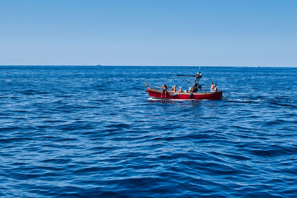 People Riding a Red Fishing Boat on the Sea · Free Stock Photo