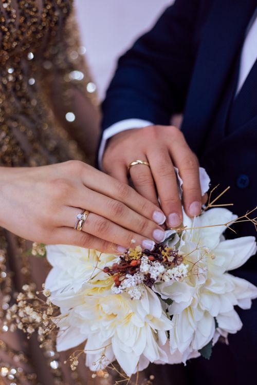Free Elegant wedding scene with couple's hands showing rings over bouquet. Stock Photo