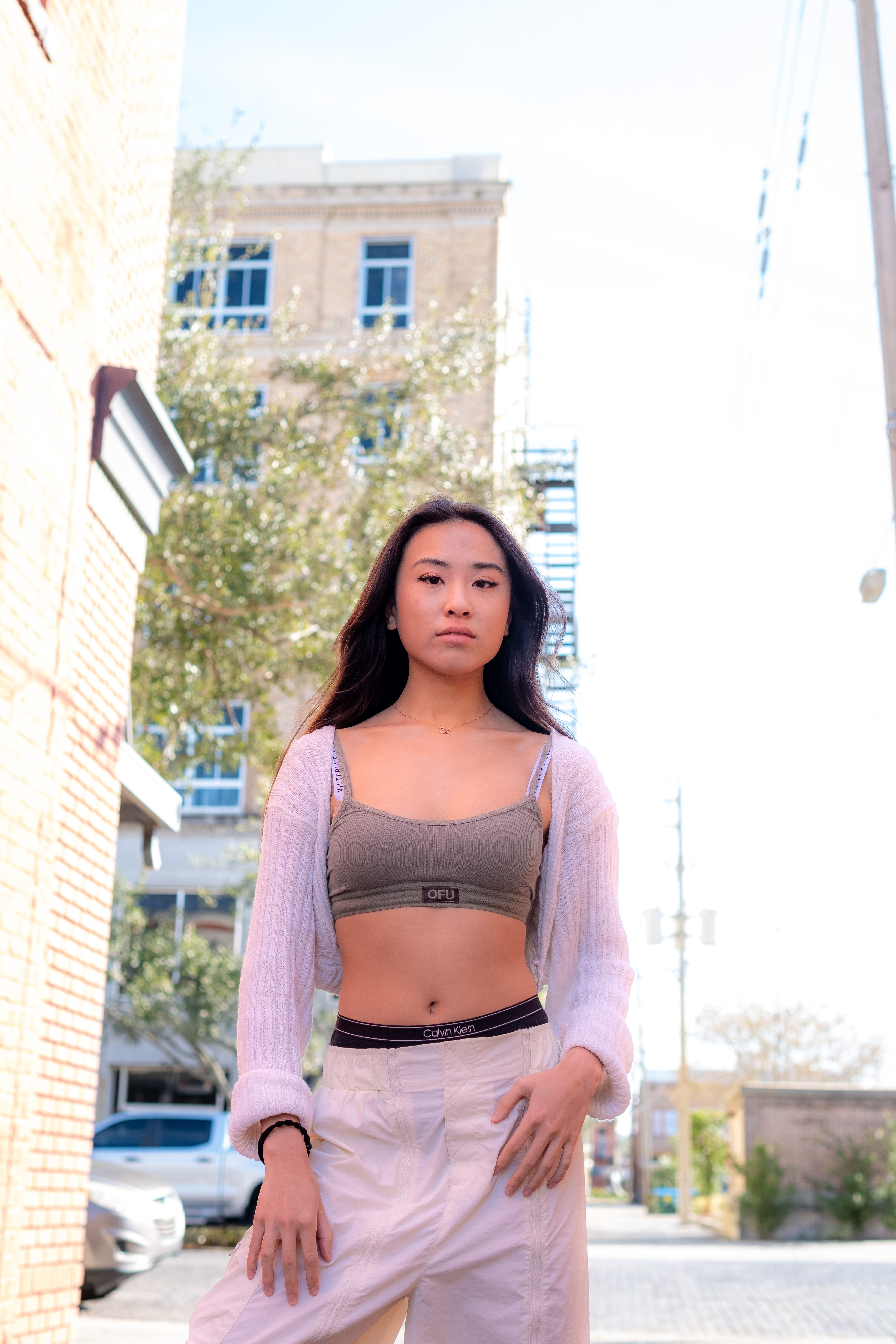 Stylish young woman posing confidently in an urban setting, showcasing modern fashion in a city backdrop.
