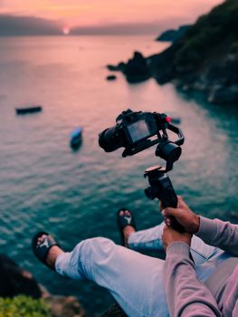 Photographer capturing a tranquil sunset by the sea with professional equipment.