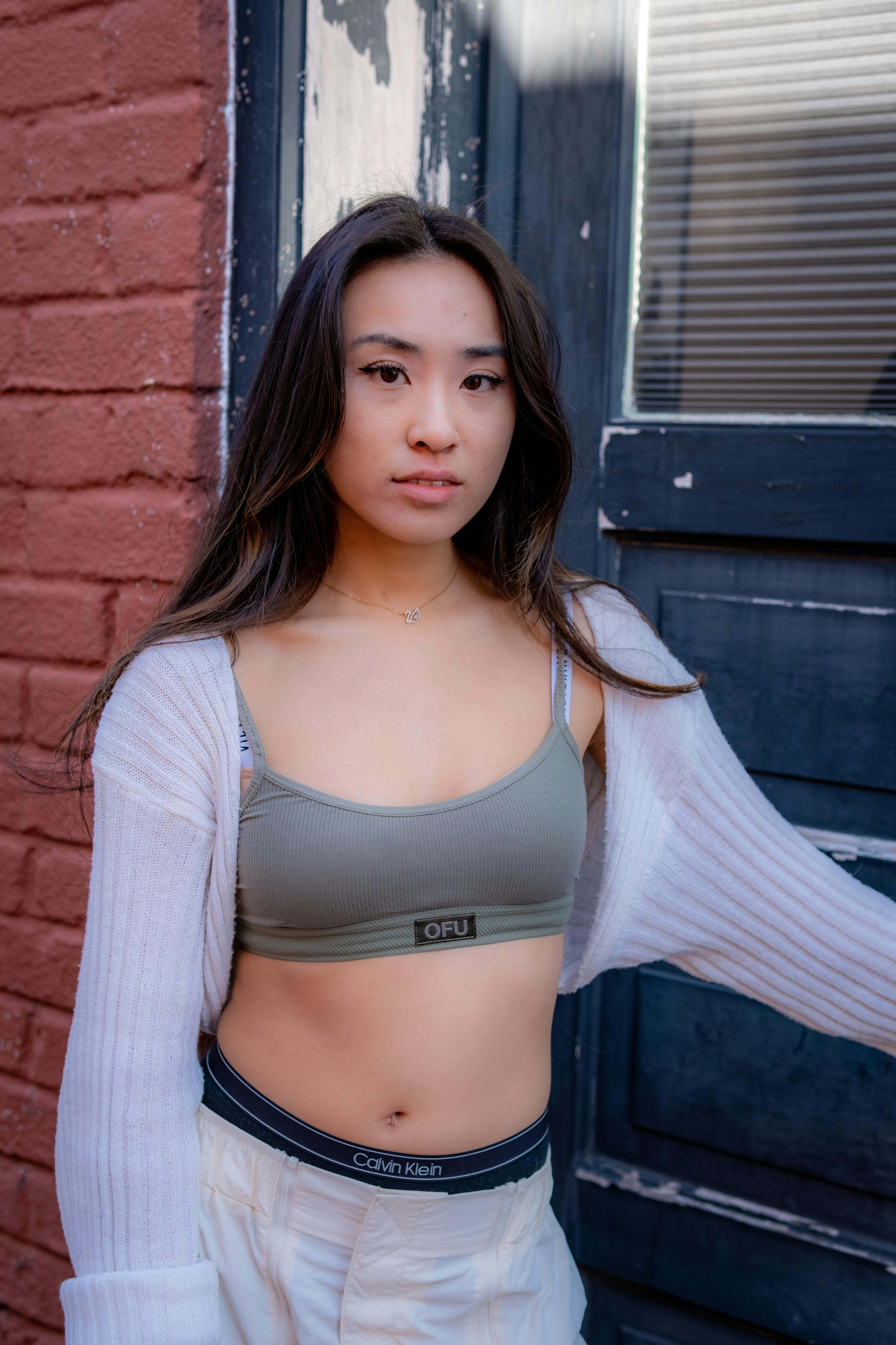 Confident portrait of a young woman in casual attire posing outdoors by a brick wall.