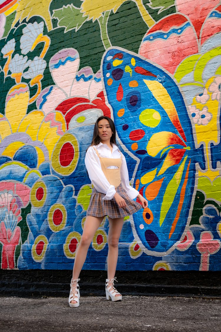 Woman In Shirt And Skirt Standing By Wall With Colorful Graffiti