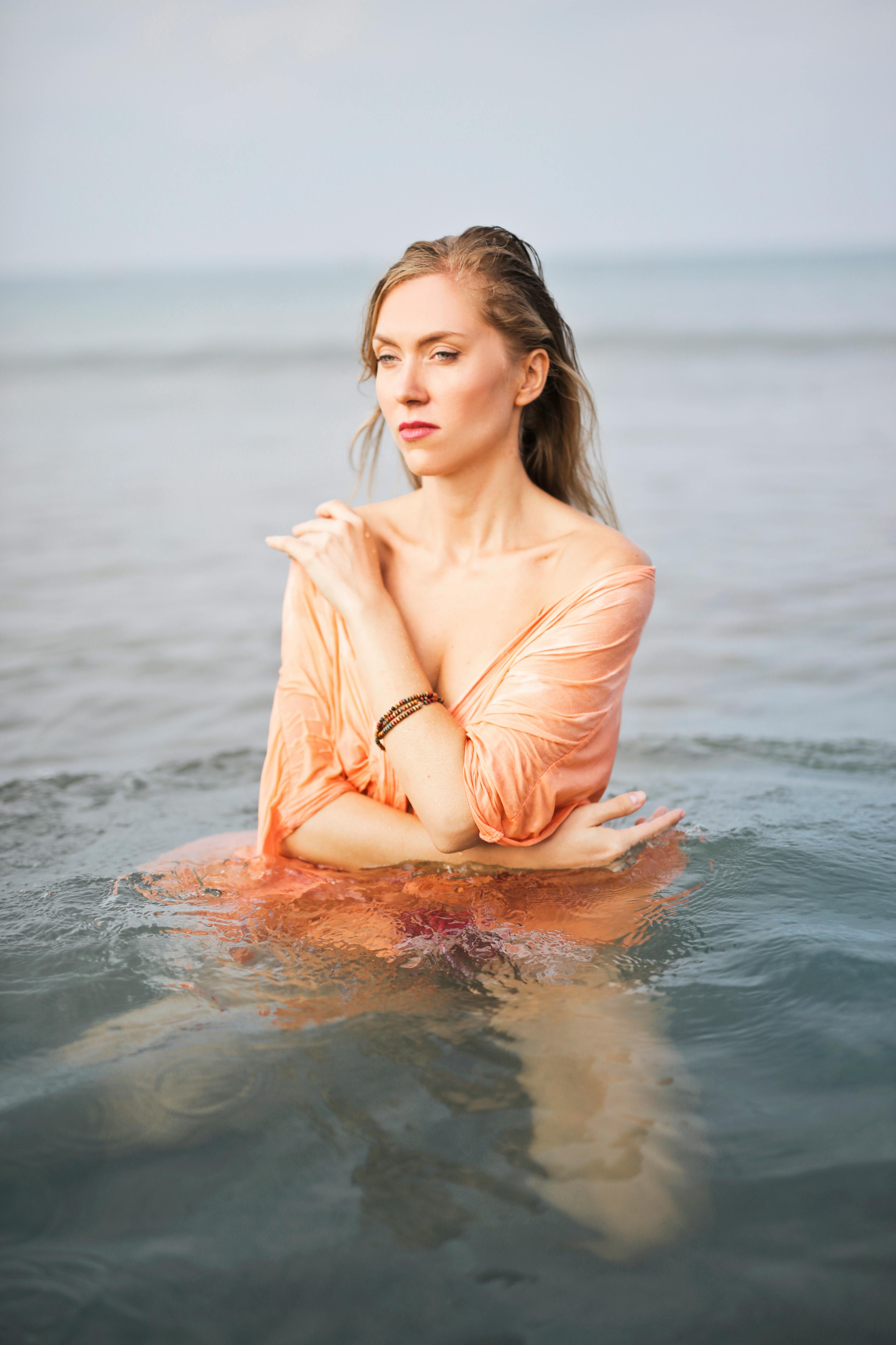 这幅宁静的肖像中，一位女子在海洋中优雅地摆着姿势，展现了自然之美与优雅