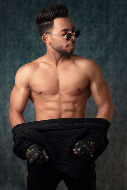 Free Portrait of a shirtless muscular man wearing sunglasses in a studio setting. Stock Photo