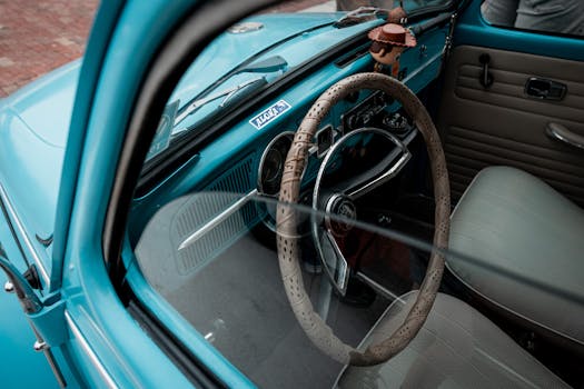 Explore the charming vintage interior of a blue Volkswagen Beetle, highlighting the classic steering wheel and dashboard.