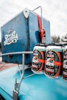 Blood Orange beer cans displayed on a vintage blue Pepsi cooler outdoors.