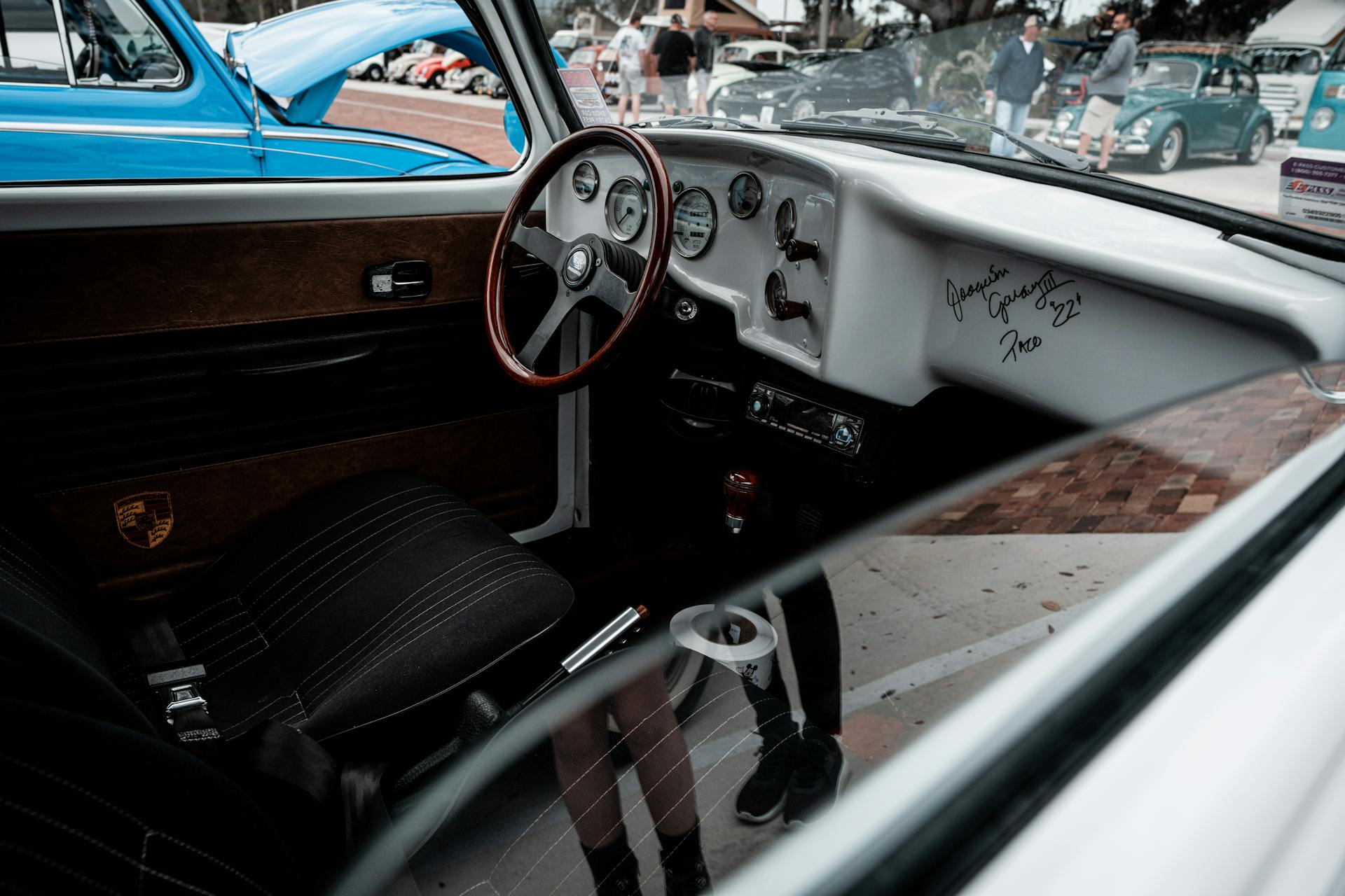 Interior of a vintage Volkswagen with autographed dashboard at a car show.